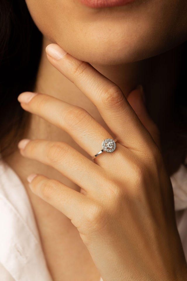 Main de femme portant une bague ronde sertie de diamants