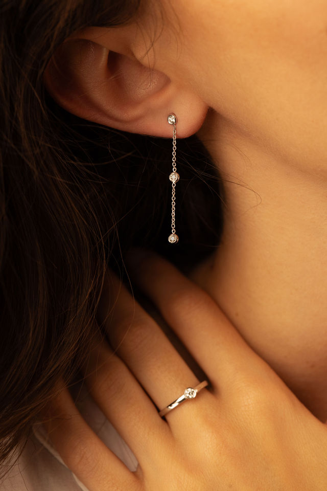 Zoom sur une boucle d’oreille pendante et une bague diamant
