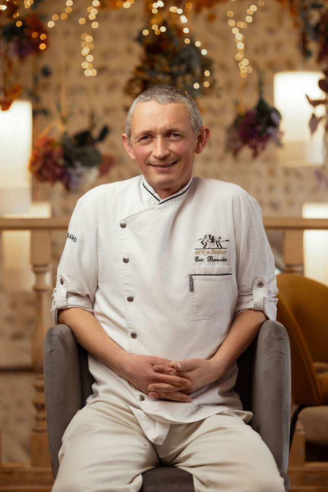 Chef cuisinier assis devant une déco lumineuse et fleurie