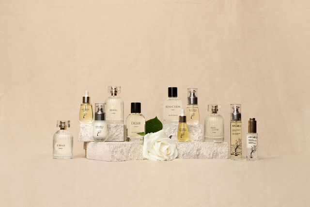 Collection de flacons de parfum exposés devant un mur beige