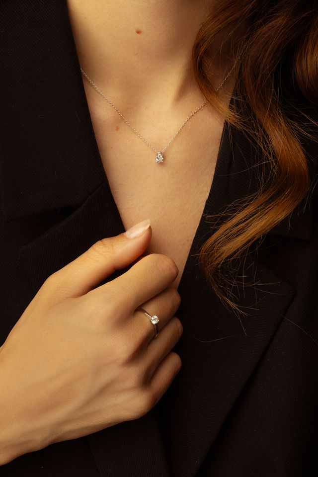 Collier fin avec pendentif diamant et bague portée sur veste noire