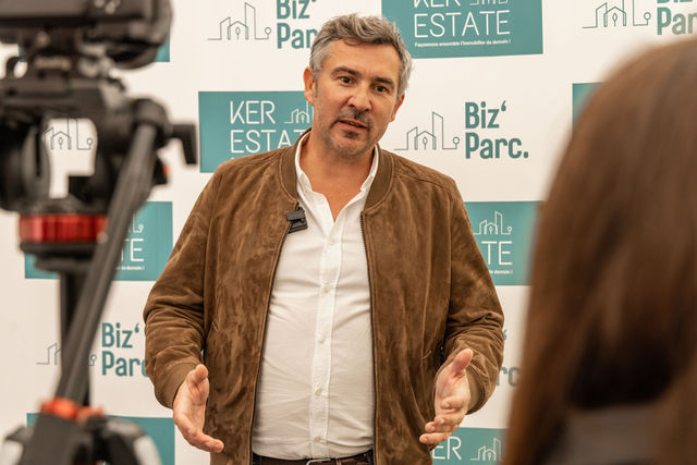 Homme interviewé devant un fond avec logos immobiliers