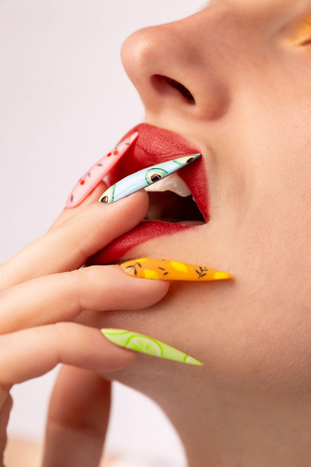 Zoom lèvres rouges et ongles décorés fruits exotiques