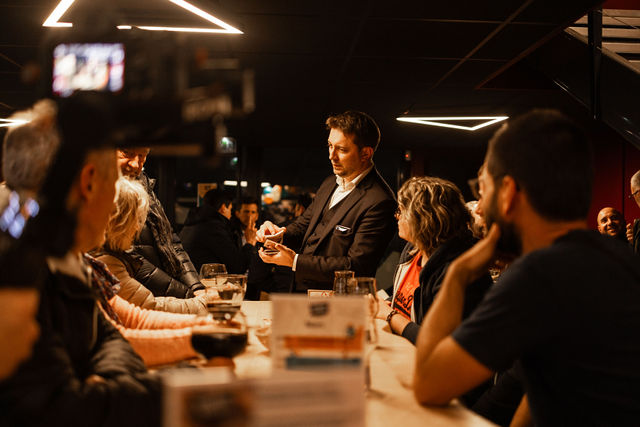 Magicien réalisant un tour de cartes devant des clients dans un bar