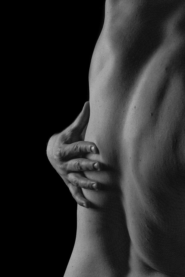 Photo en noir et blanc d’une main posée sur un dos musclé