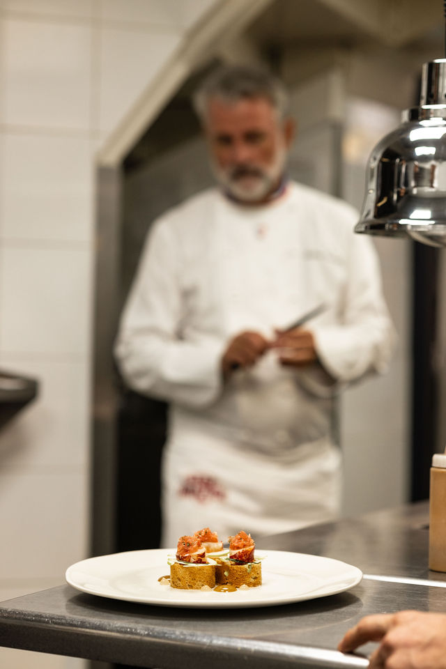 Assiette gastronomique au premier plan avec chef en arrière-plan, ambiance cuisine étoilée