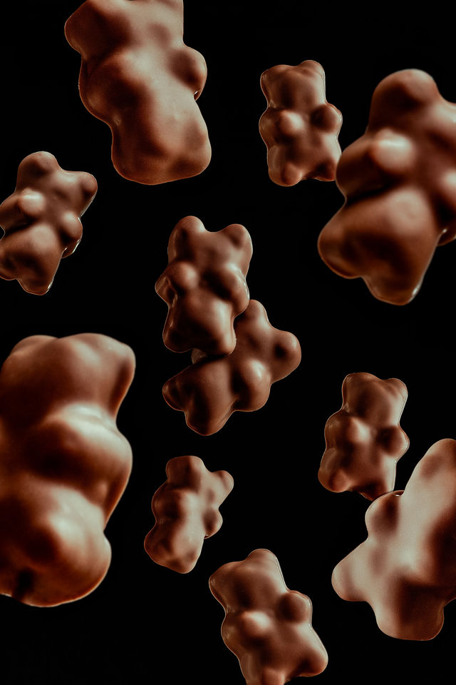 Oursons enrobés de chocolat en lévitation sur fond noir, photo créative de confiserie