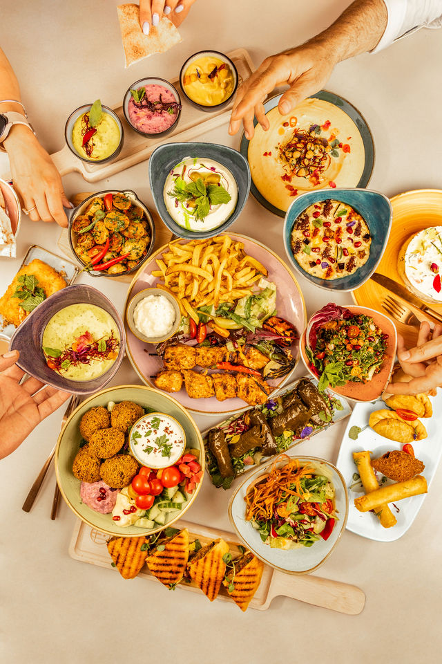 Grande table de mezzés libanais colorés, ambiance conviviale et plats à partager