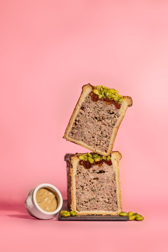 Pâté en croûte à la pistache présenté en studio sur fond rose avec moutarde