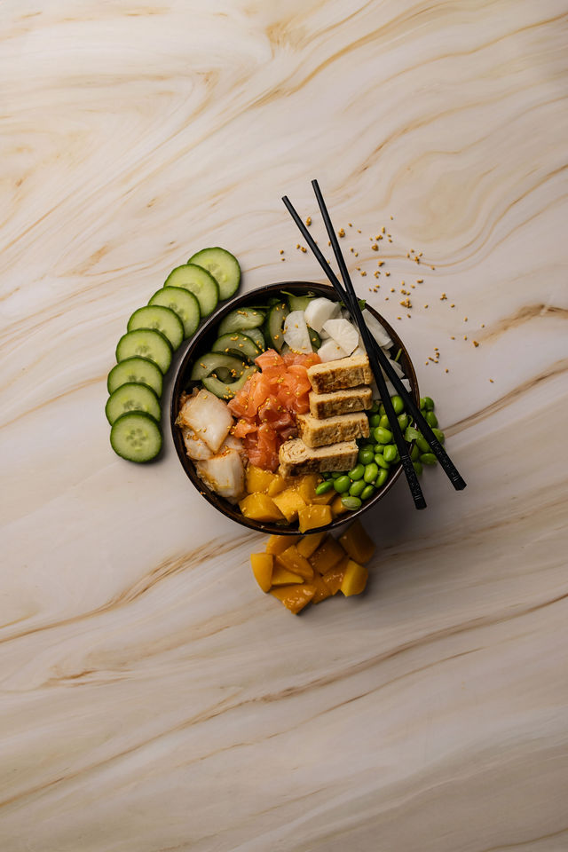 Poke bowl au saumon, mangue, tofu et légumes frais avec baguettes noires