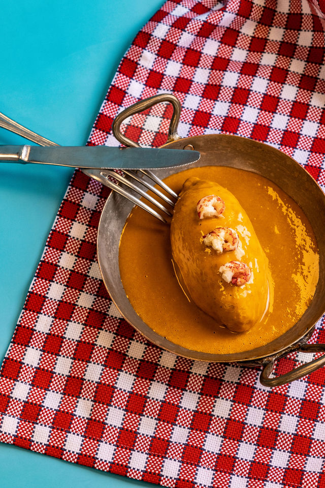 Quenelle nappée de sauce au homard servie dans un plat en métal, stylisme rétro
