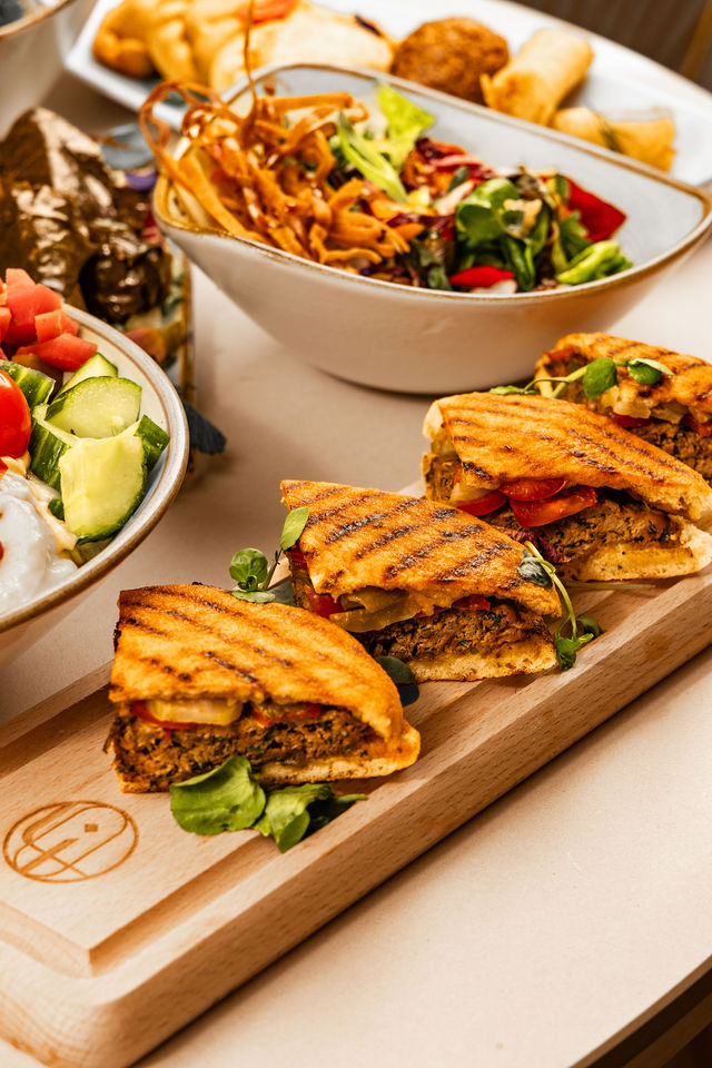 Trio de sandwichs grillés végétariens sur planche en bois, accompagnés de salade
