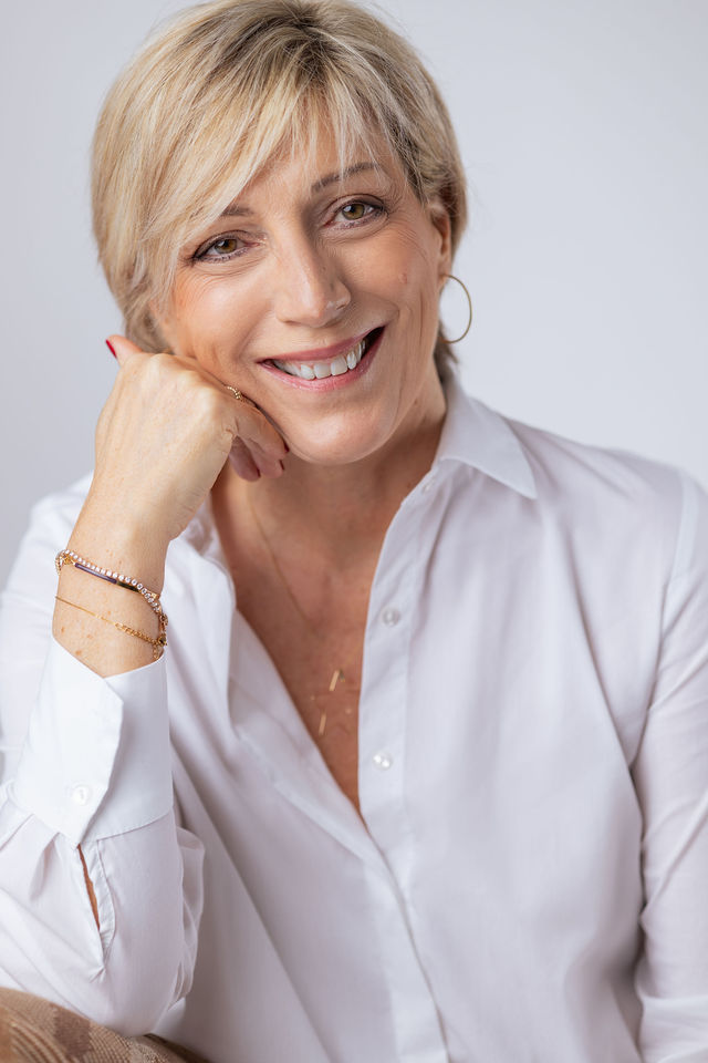 Portrait d’une femme blonde souriante en chemise blanche