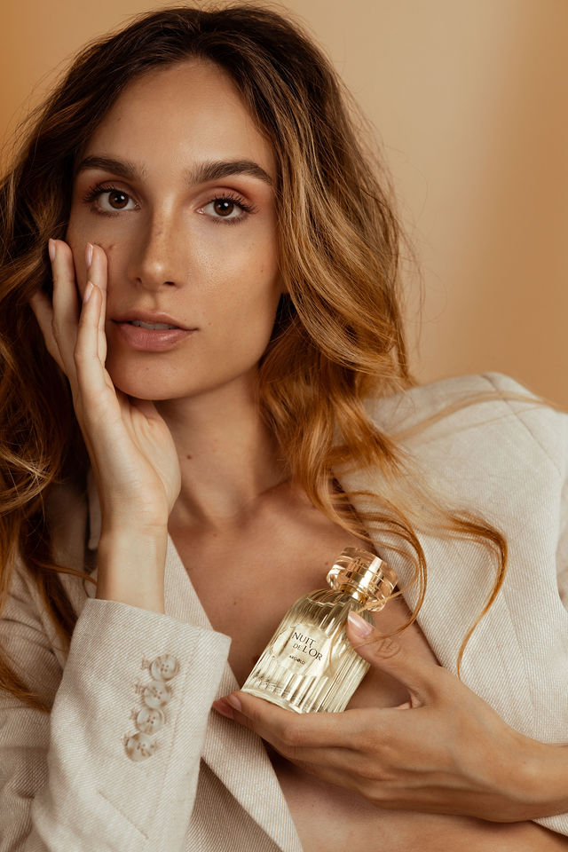 Femme tenant un flacon de parfum Nuit de l’Or en buste