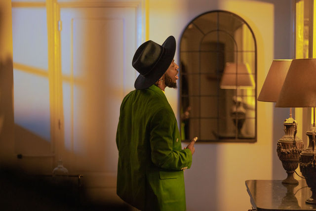 Homme de profil en veste verte et chapeau dans un intérieur élégant