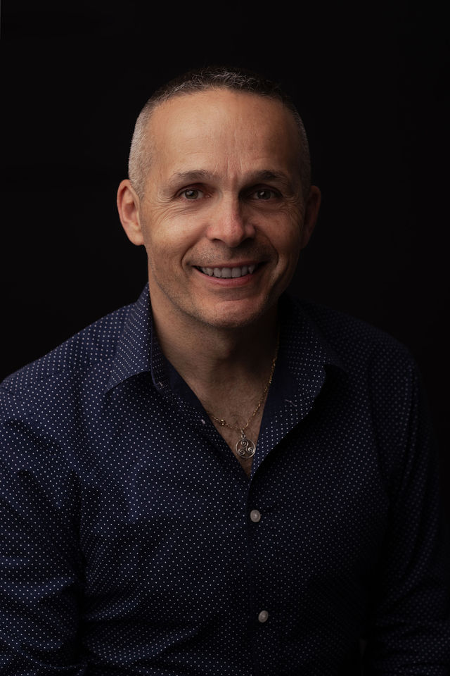 Portrait d’un homme souriant en chemise à pois sur fond noir