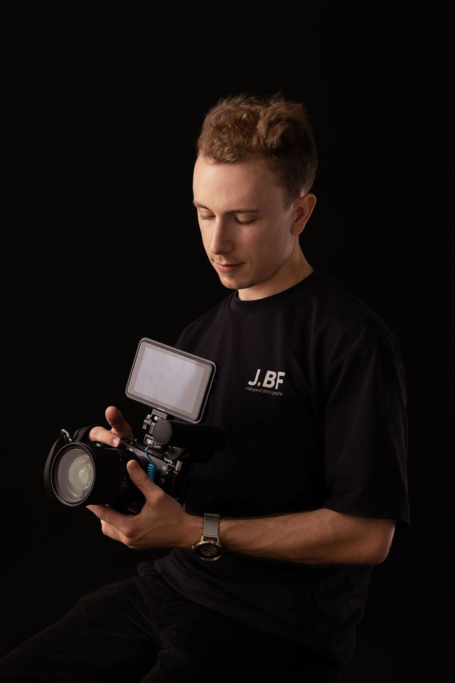 Portrait d’un vidéaste en t-shirt noir tenant une caméra professionnelle