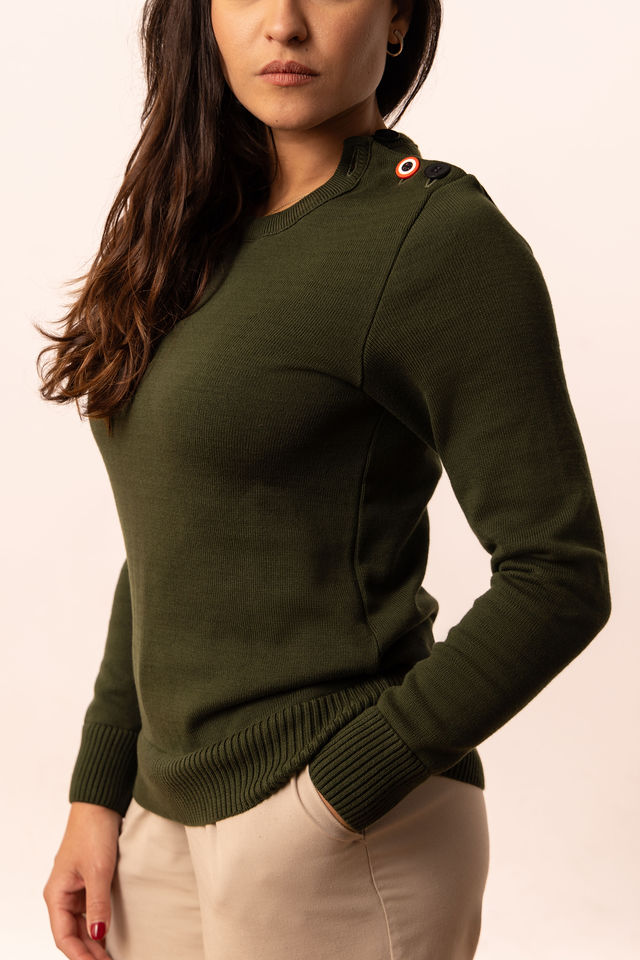 Femme portant un pull vert kaki avec écusson tricolore à l’épaule